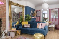Grand miroir décoratif sur pied encadré de culpabilité et canapé bleu dans un salon/salle à manger bleu et rose