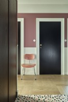 Chaise dans un couloir rose moderne à côté d'une porte en bois noire