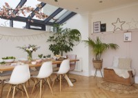Salle à manger contemporaine dans un espace ouvert avec une décoration de branches de fleurs, du parquet et des boiseries roses.