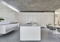 Cuisine-salle à manger contemporaine avec mobilier blanc et sol en béton