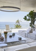 Salon contemporain blanc avec baie vitrée et vue mer