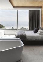 Chambre minimaliste avec baignoire et grandes baies vitrées