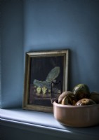 Bol de fruits et peinture à côté d'un mur peint en bleu sur une étagère
