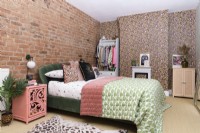 Chambre moderne en rose et vert avec un mur et un manteau de cheminée recouverts d'un papier peint à imprimé léopard et un mur avec des briques apparentes