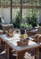 Verrerie et cactus en pot sur une table en osier dans un coin salon extérieur