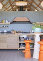 Tabourets de bar orange vif dans une cuisine contemporaine avec mur carrelé