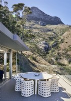 Table et chaises blanches sur terrasse avec vue sur les montagnes
