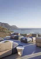 Canapés fauteuils et poufs sur grande terrasse avec vue mer