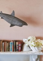 Détail de la sculpture de requin au-dessus des livres sur la cheminée