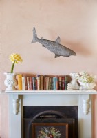Sculpture de requin flottant au-dessus des livres sur la cheminée de la cheminée