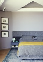 Literie grise et jaune sur le lit dans la chambre moderne