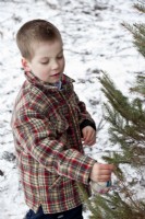 Jeune garçon portant une veste à carreaux décoration de sapin de Noël en plein air