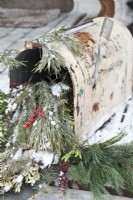 Ancienne boîte aux lettres décorée pour Noël avec de la verdure naturelle et des baies.