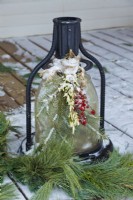 Lanterne extérieure de Noël décorée de verts et de baies attachées avec un ruban de toile de jute