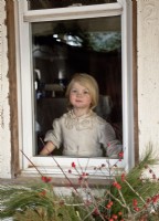 Petite fille portant une robe vintage regardant le Père Noël depuis une fenêtre