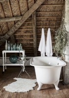 Baignoire autoportante à cylindre blanc dans une salle de bains mansardée rustique