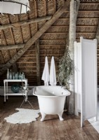 Bain autoportant dans une salle de bain champêtre avec plafond de paille