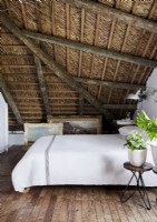 Chambre à coucher de pays avec le plafond en bois dans l'espace de grenier
