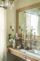 Salle de bain élégante et féminine avec miroir vintage, vanité en bois et lustre.