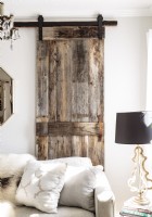Une porte de grange coulissante construite à partir de bois récupéré ajoute une note rustique texturée au salon.