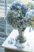 Des hortensias bleu pâle nichés dans un ancien contenant ajoutent une note romantique à la chambre.