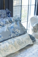 Renee garde le thème bleu et blanc français de la chambre à coucher fluide avec des oreillers arborant des variations de teintes et des motifs floraux et pastoraux.