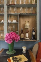 Dans le salon, un espace salle à manger intime dispose d'une étagère encastrée abritant la collection de verres vintage et de tasses à café françaises de Renee.