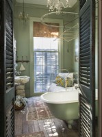 Des volets mènent à la salle de bain, où une baignoire sur pattes et un évier en marbre turc sur de vieux pavés en pierre créent une ambiance d'antan.