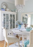 Un miroir au sol ajoute de la dimension à la petite salle à manger tandis que l'armoire fournit un affichage et offre un stockage sûr pour la vaisselle organisée.