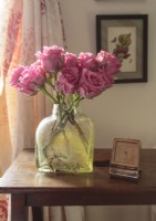 Une bouteille vintage constitue un récipient approprié pour les roses dans une teinte en harmonie avec les accents roses de la chambre à coucher.