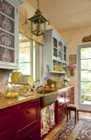 Les bleus doux, les rouges country et les jaunes ocre sont à la base du décor de la cuisine. Les armoires supérieures correspondent à la garniture de la pièce tandis que les armoires inférieures arborent une riche teinte cramoisie.