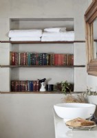 Évier de cuvette dans la salle de bains avec des serviettes et des livres sur des étagères