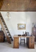 Bureau en bois dans une étude de pays avec escalier de style échelle à côté