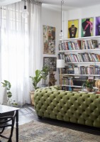 Canapé clouté vert dans le salon avec de grandes étagères et des œuvres d'art