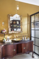 Salle de bain avec meuble-lavabo vintage et murs dorés