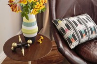 Un fauteuil en cuir est rehaussé d'un coussin coloré au motif géométrique.