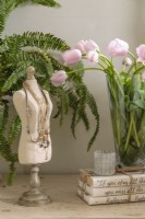 Une forme de couturière de table fait un caddie sculptural pour les colliers. La verdure et les fleurs ajoutent des touches de couleur pure à sa palette neutre.