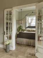 Dans la chambre principale, les sols en travertin sont un choix écologique qui offre un motif subtil et un entretien facile. Les miroirs remplacent le verre dans les portes françaises récupérées.