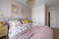 Chambre avec un grand lit habillé de couleurs pastel
