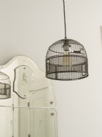 Une vieille cage à oiseaux est câblée dans le luminaire de la salle de bain.