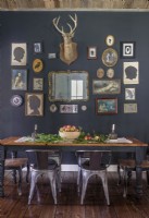 Un mur d'accent peint en gris foncé désigne une salle à manger dans l'espace ouvert tout en offrant une vitrine spectaculaire pour les objets de famille assortis et une monture de cerf vintage.
