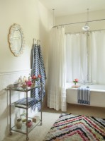 Les serviettes à rayures et le tapis arc-en-ciel en zigzag ajoutent du piquant à une baignoire entièrement blanche. Dans un espace neutre comme celui-ci, il est facile de changer radicalement l'apparence de la pièce simplement en jouant avec les accessoires.