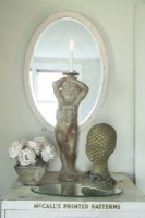 Une statue de chérubin, des roses en tissu et une forme de tête scintillante créent une vignette romantique sur une vieille armoire en métal dans la chambre.