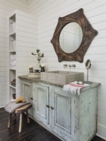 Un meuble détourné avec une vasque en calcaire donne le ton à la salle de bain. Les planchers en bois foncé contrastent avec le mur lambrissé blanc dans tout le loft.