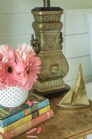Une lampe en métal en forme d'urne et un petit voilier en laiton ornent une table de chevet.
