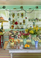 Des étagères présentent des collections de vases, d'arrosoirs et de seaux de sable. La lampe est dotée d'un abat-jour unique en son genre.