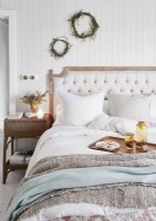 Chambre à coucher rustique avec des couronnes rustiques sur un mur blanc au-dessus du lit