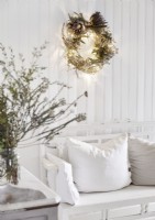 Couronne de Noël illuminée sur un mur blanc au-dessus du canapé