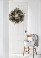 Cadeau de Noël sur chaise en bois et couronne rustique sur porte blanche