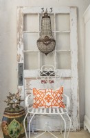 Un lustre en cristal égyptien s'unit à une porte vintage et à une chaise de jardin.